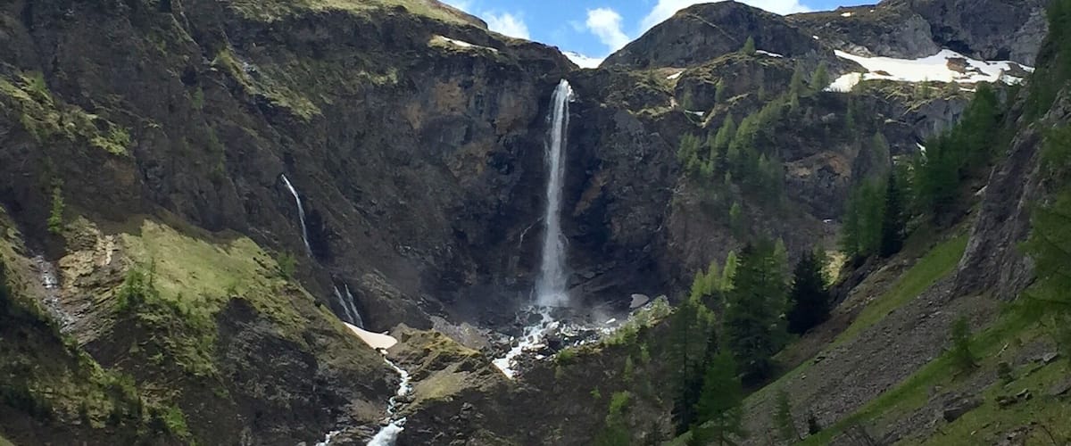 A mountainous landscape with a waterfall cascading down a rocky cliff.