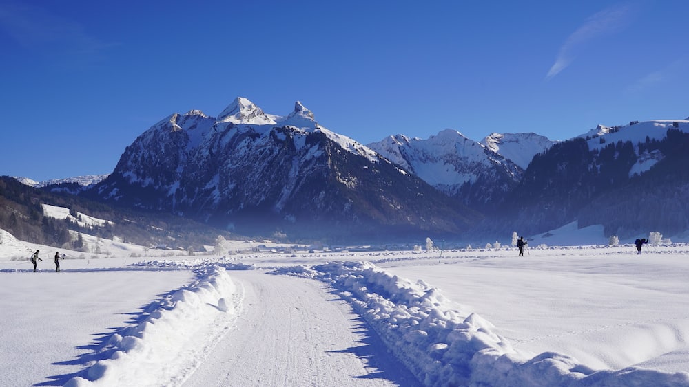 Hiking trail in winter for walks among the snow covered fields on a clear cold day. It is in cross country skiing region Studen in Switzerland. There are mountains all around.