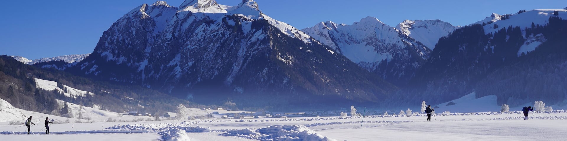 Hiking trail in winter for walks among the snow covered fields on a clear cold day. It is in cross country skiing region Studen in Switzerland. There are mountains all around.