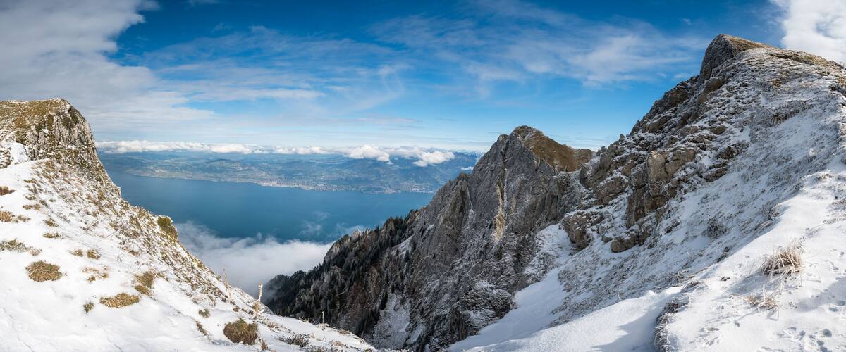 A snow-covered mountain peak with a lake and distant cityscape.