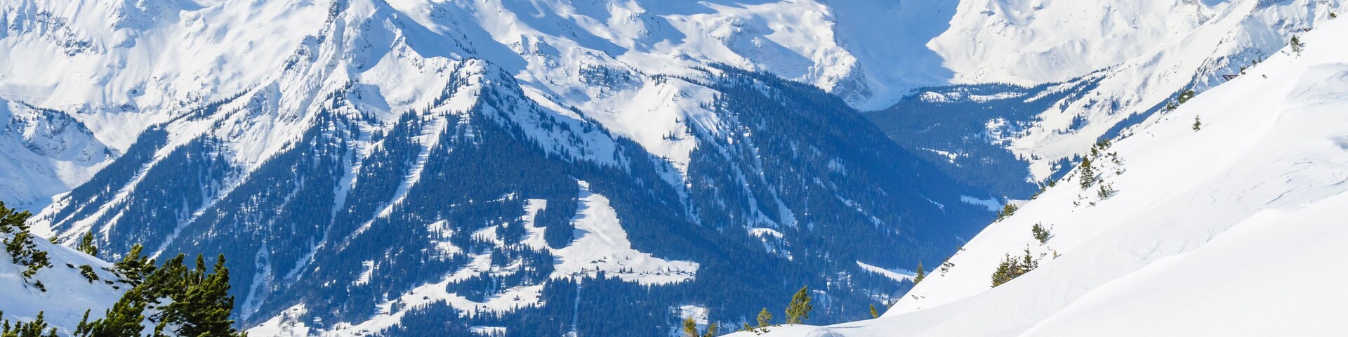 A snowy mountain landscape with three skiers descending a slope.