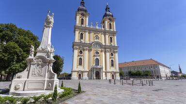 Una iglesia histórica con dos torres y una estatua al frente.