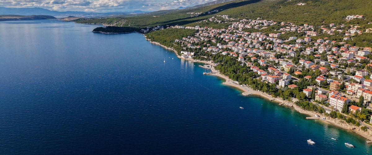 A coastal town with a bay, boats, and a mountainous backdrop.