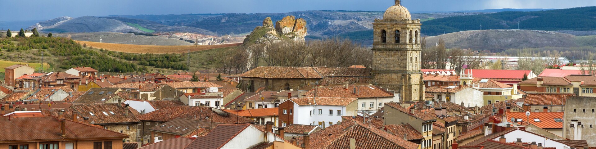 A town with historic buildings, a prominent church, and rolling hills in the background.
