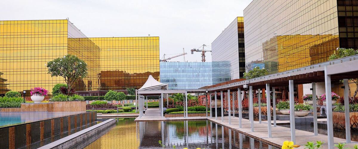 A modern urban plaza with a reflective pool, a gazebo, and contemporary buildings.