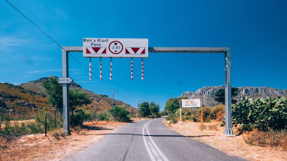 A road with a sign indicating 'Bain's Kloot Pass' and a height restriction of 3.87 meters.