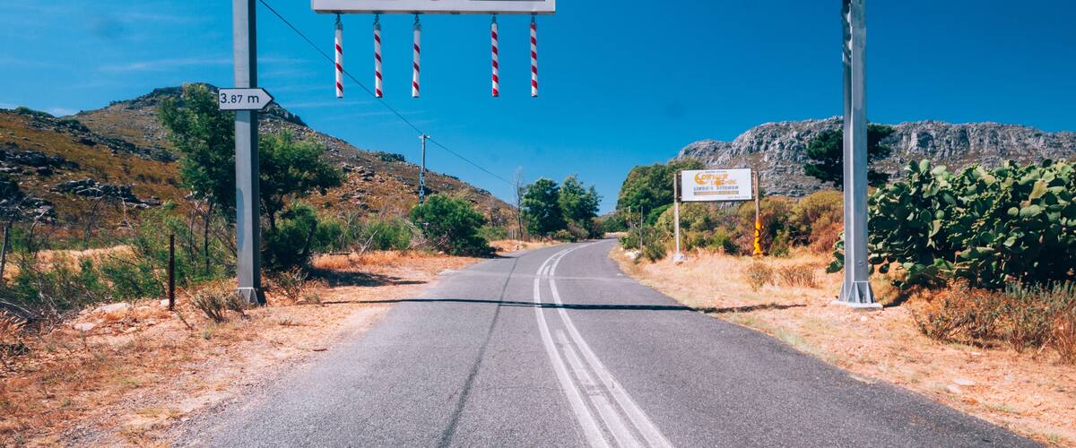 A road with a sign indicating 'Bain's Kloot Pass' and a height restriction of 3.87 meters.