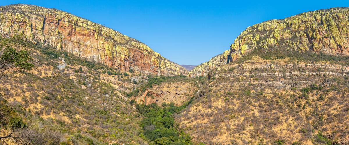 A canyon with steep, rocky cliffs and sparse vegetation.