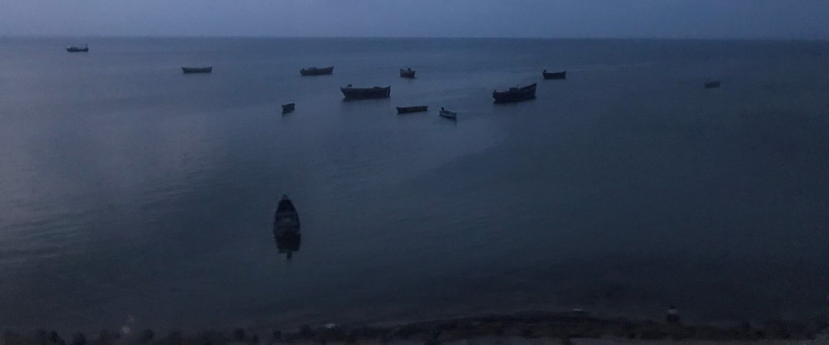 A calm sea with several boats scattered across the water.