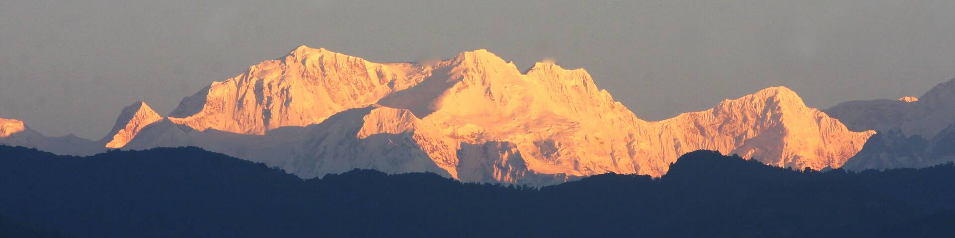 A mountain range with snow-capped peaks bathed in golden sunlight.