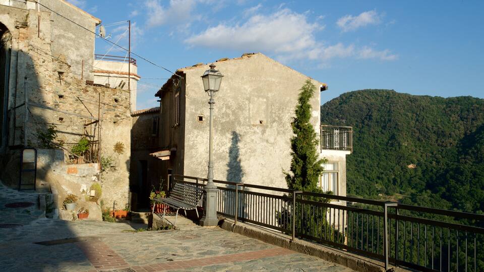 A stone building with a metal railing overlooking a forested hillside.