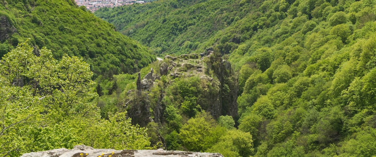 A lush green valley with a stone ruin in the center.