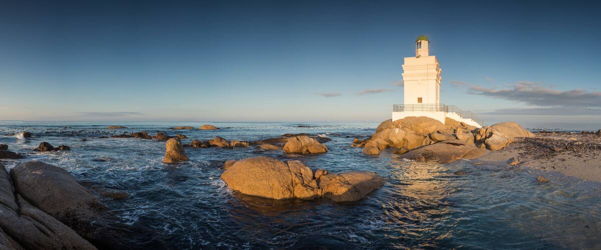 A lighthouse on rocky outcrops by the sea.