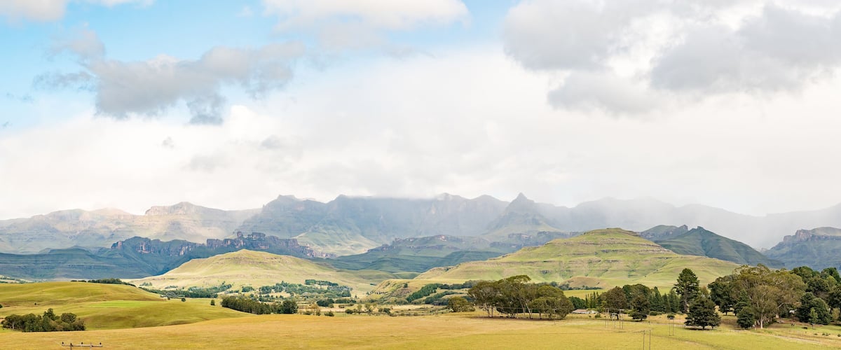 Rolling hills, a valley, and distant mountains under a partly cloudy sky.