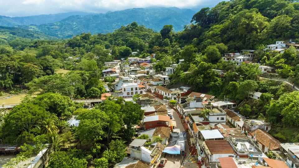 A hillside village with terraced houses and lush greenery.