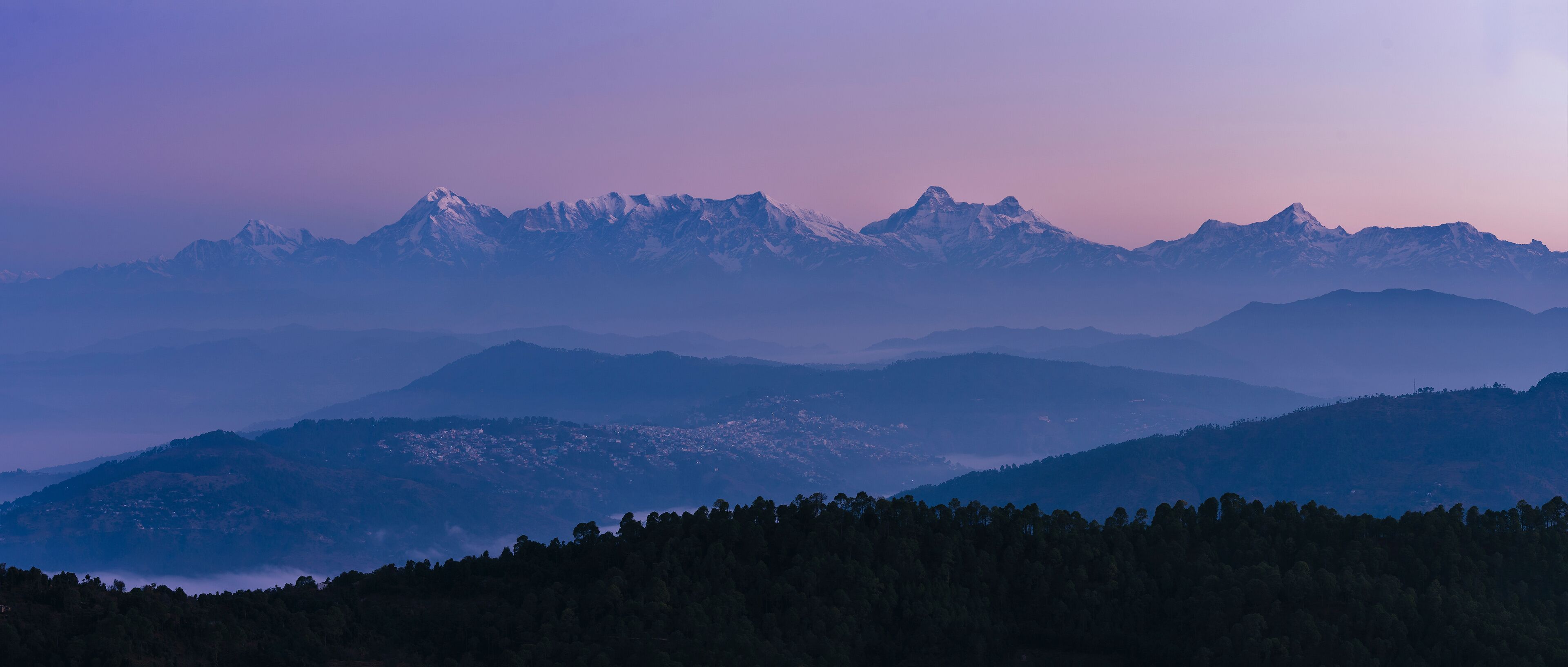Aerial view of Garwal Himalayas at dawn with snow-capped peaks and serene valley, Mukteshwar, Uttarakhand, India.