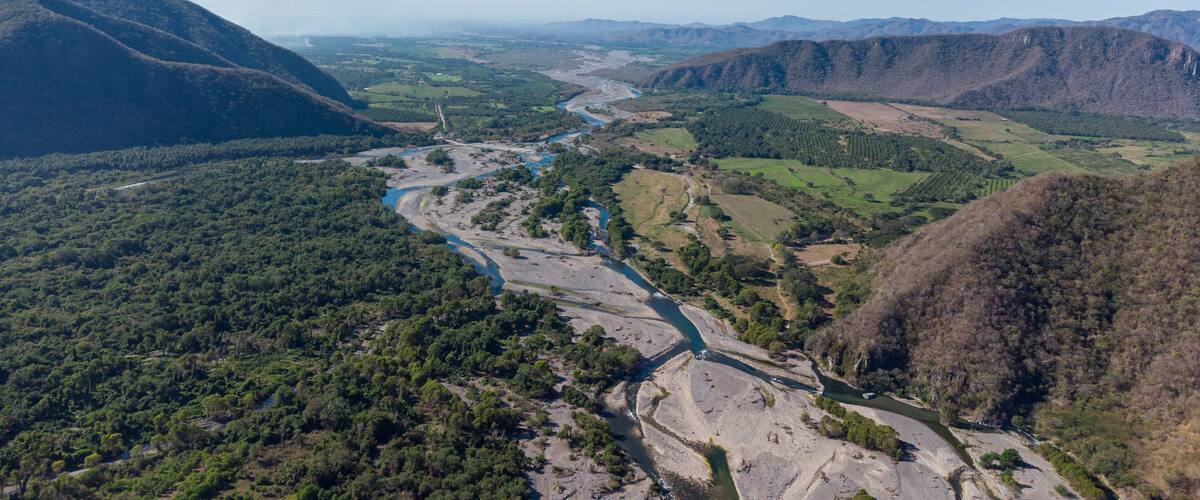 A river winding through a valley with surrounding hills and greenery.