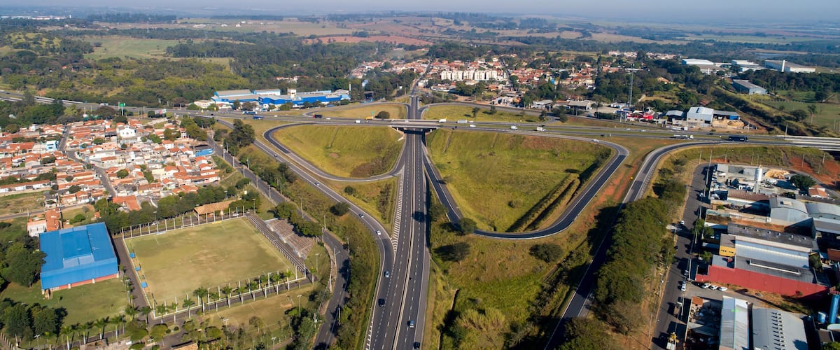 An aerial view of a highway interchange with multiple lanes, surrounded by residential areas and greenery.
