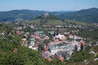 Un pueblo ubicado en un valle, con una iglesia destacada en la cima de una colina y colinas verdes circundantes.