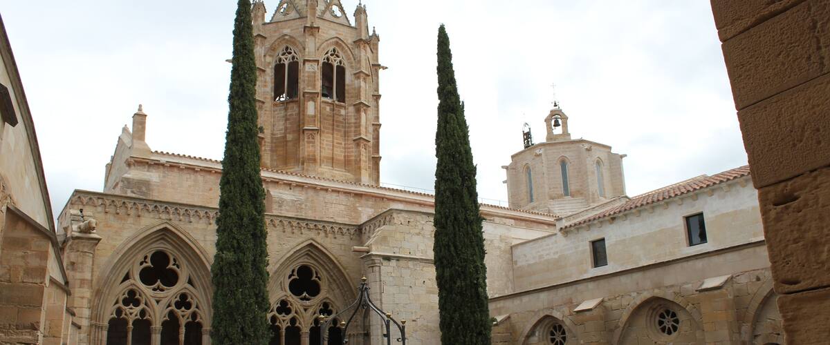 Monastery of Santa Maria de Vallbona The Monastery of Santa Maria de Vallbona (Catalan: Santa Maria de Vallbona de les Monges; Spanish: El Real Monasterio de Santa MarĂa de Vallbona) is a Cistercian abbey in Vallbona de les Monges, in the comarca of Urgell, Catalonia, Spain. Founded in the early 12th century, it is one of the most important monasteries in Catalonia; its church represents an example of transition between Romanesque and Gothic architecture. The abbey was declared a national monument in 1931. Initially the monastery consisted in a community of hermits, documented from 1157, which followed the Benedictine rule; in 1175, however, only a small group of nuns remained. In 1163 they had received territories from Ramon Berenguer IV, count of Barcelona, and in that year decided to switch to the Cistercian order. Two years later the abbey received several privileges from King Alfonso I of Aragon, and subsequently it could expand thanks to the numerous donations from noble families. The cloister is on a quadrangular plan, whose sides, of different lengths, correspond to different, successive ages and construction styles (12th-15th centuries). The oldest sector, on the south, shows the original, sober Romanesque-Cistercian canons: it has three spans formed by three piers, with three rounded arcades supported by columns with undecorated capitals. The eastern wing is also in Romanesque style (early 13th century), and has five spans divided by four pilasters, The arcades form triple mullioned windows with, in the mullions, small rose windows with decoration in Arabic style. The capitals of the columns have vegetable motifs. The northern wing is the shortest one; it has wide hollows with ogival traceries in Gothic style, dating to the 14th century. The western side, the most recent one, was built in the 15th century in proto-Renaissance style. The capitals of the columns show the heraldic symbols of the CaldĂ©s family, who produced the monastery's abbesses during that period. The Capitular Hall is accessed from the cloister through a Gothic gate built under abbess Anglesola in the 14th century, and has a cross-vault cover. The pavement features several tomb slabs of abbesses, and there is an alabaster image of the Virgin of Mercy, attributed to the sculptor Pere Johan. (source: en.wikipedia.org/wiki/Monastery_of_Santa_Maria_de_Vallbona)