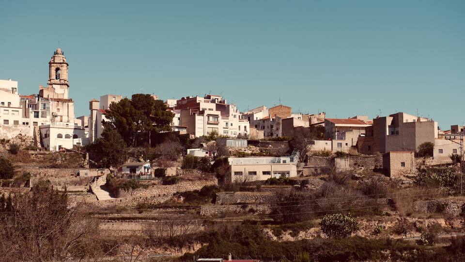 A town with a prominent church tower, terraced buildings, and a mix of vegetation.