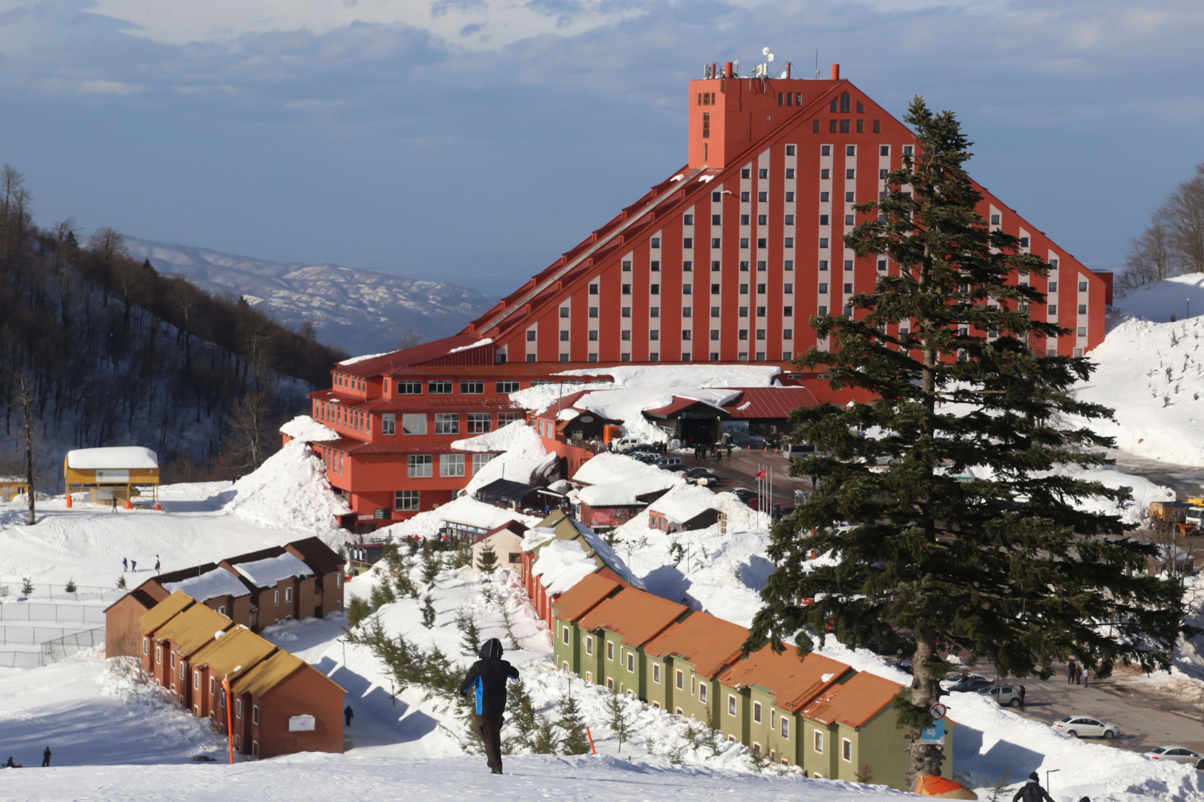 A large red building with a steep roof, surrounded by snow-covered ground and trees.