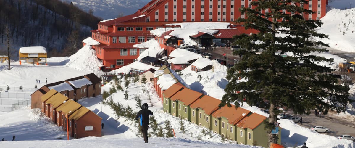 A large red building with a steep roof, surrounded by snow-covered ground and trees.