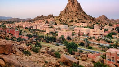 A desert town with buildings, a prominent rock formation, and sparse vegetation.