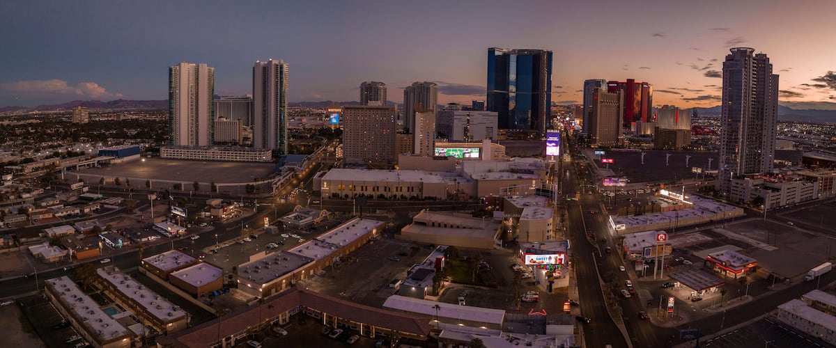 A cityscape at dusk with illuminated buildings and a clear view of the surrounding landscape.