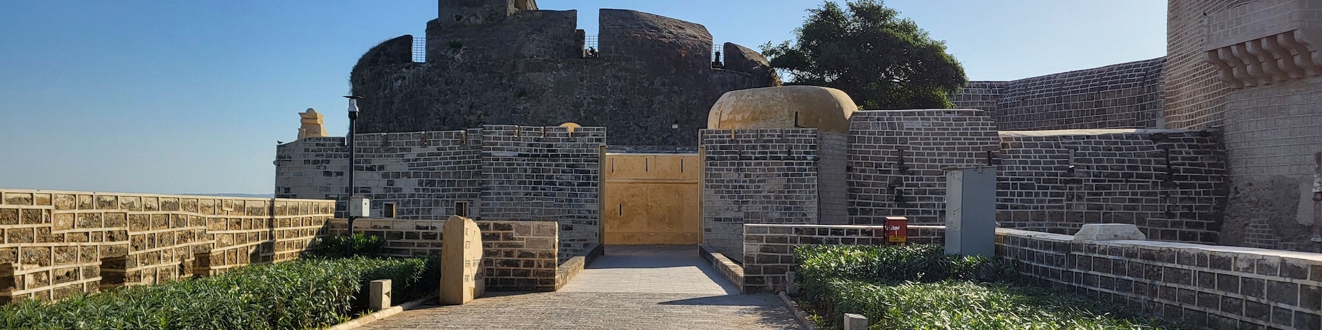 Un sendero de piedra que lleva a una fortaleza histórica con una gran puerta y una torre de vigilancia.