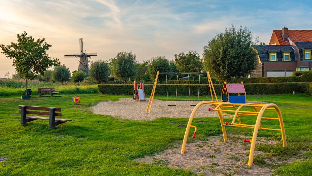 Child-friendly dutch neighborhood with playground and a traditional windmill in the village of Terheijden, North Brabant, The Netherlands