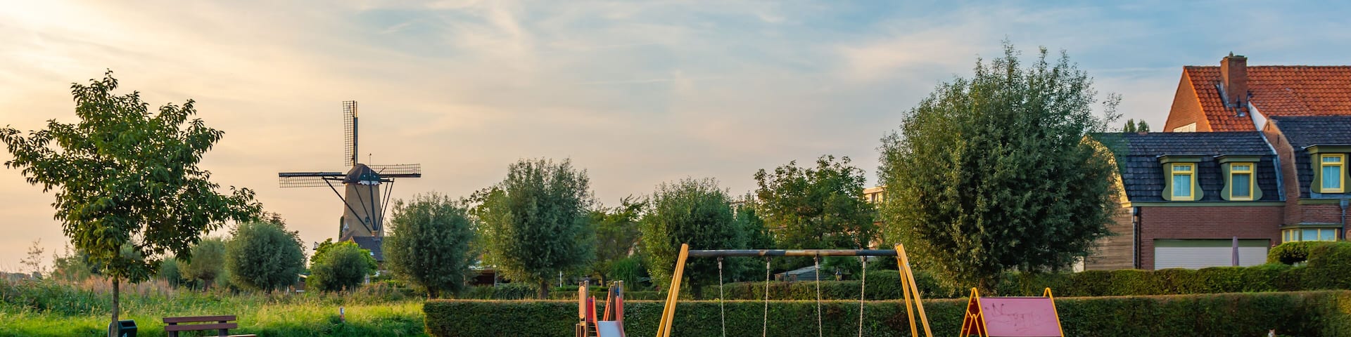 Child-friendly dutch neighborhood with playground and a traditional windmill in the village of Terheijden, North Brabant, The Netherlands