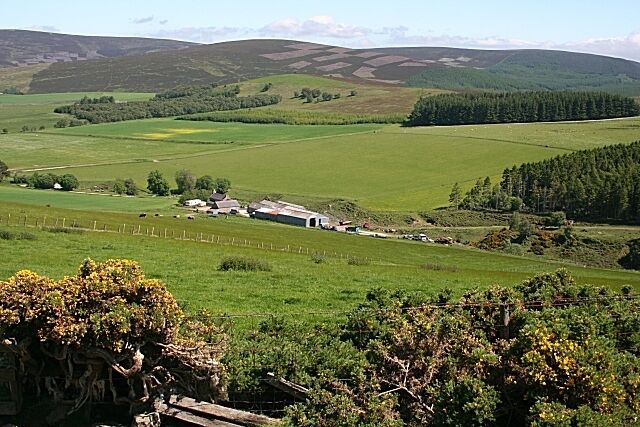 A rural landscape with rolling hills, a farmhouse, and a fenced field.