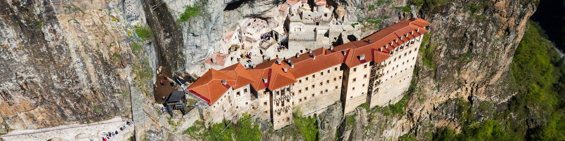 Breathtaking top-down drone perspective of the historic Greek Orthodox Sumela Monastery nestled among dense green pine woods in Trabzon, Turkey