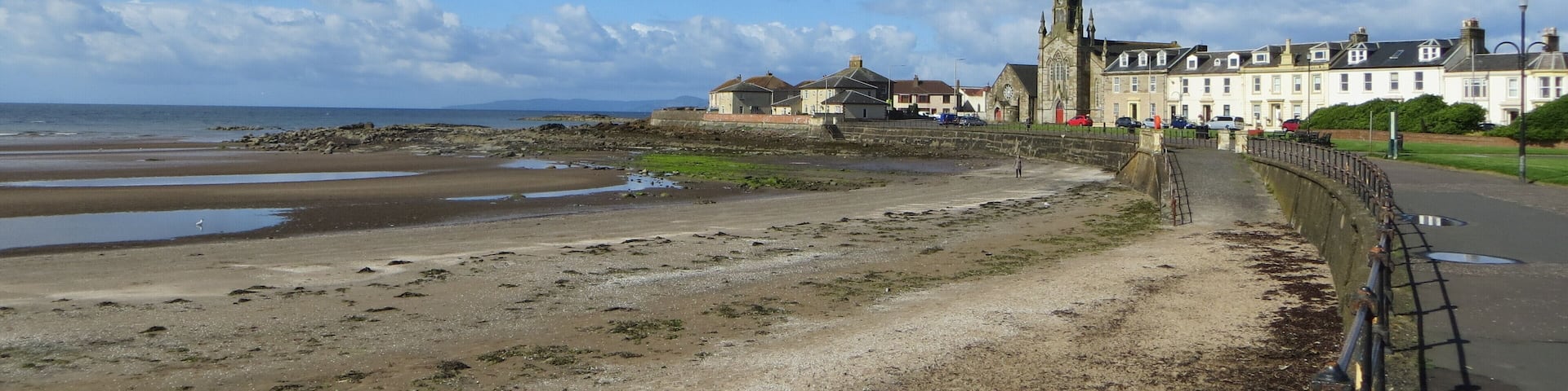 A beach with a church and residential buildings in the background.