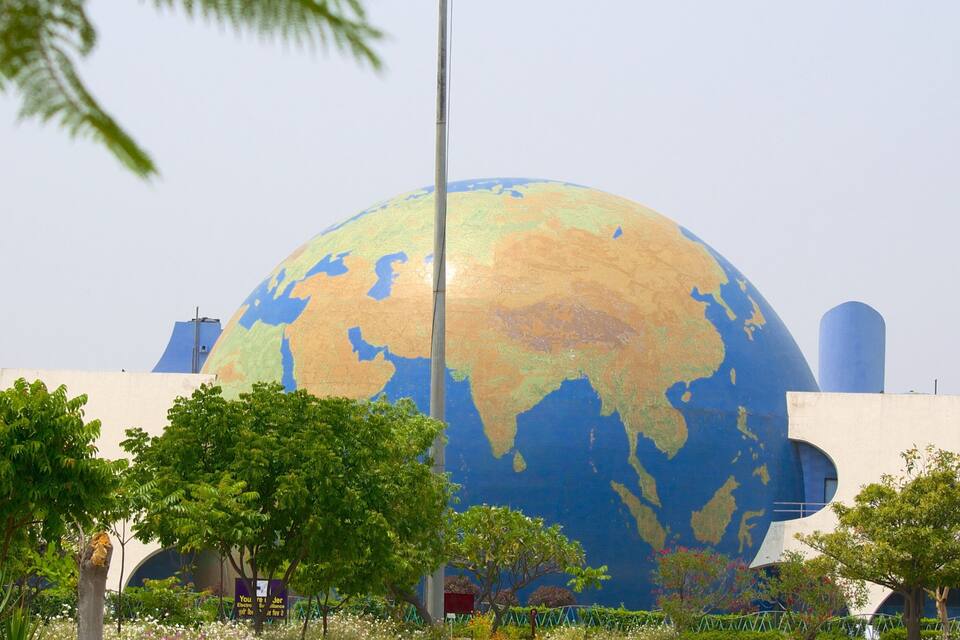 A large globe sculpture surrounded by trees and buildings.