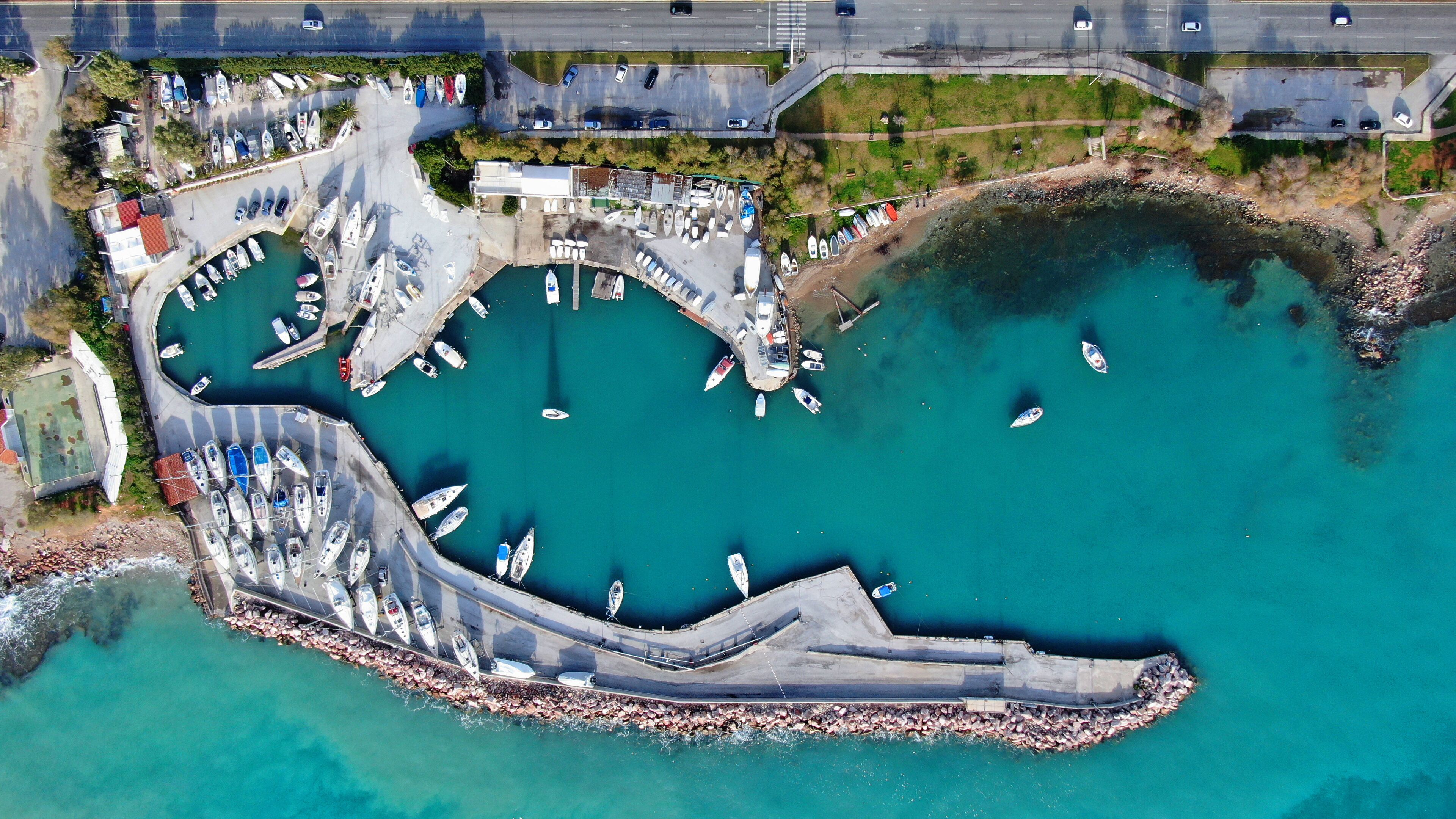 An aerial view of a marina with boats docked and a curved breakwater.
