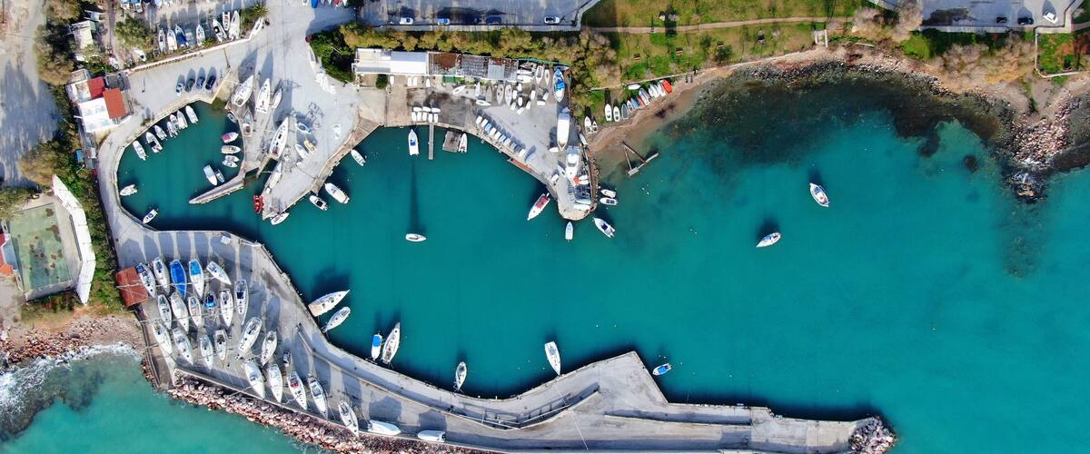 An aerial view of a marina with boats docked and a curved breakwater.