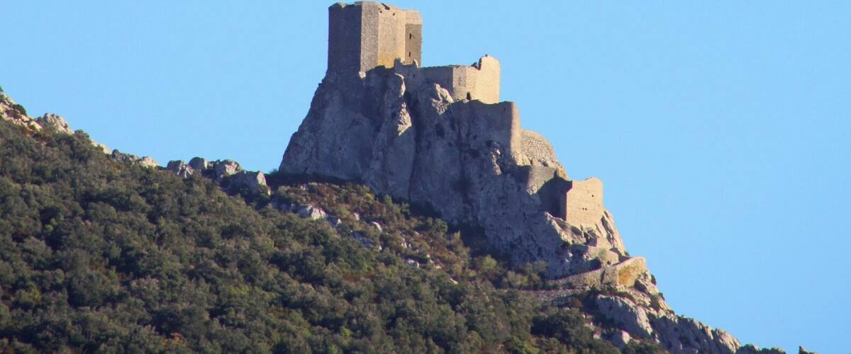 A castle on a hill with a clear sky and a crescent moon.