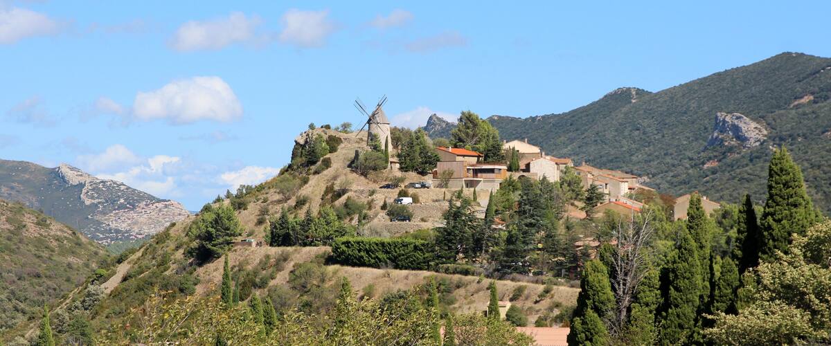 A hillside village with traditional buildings and a windmill.