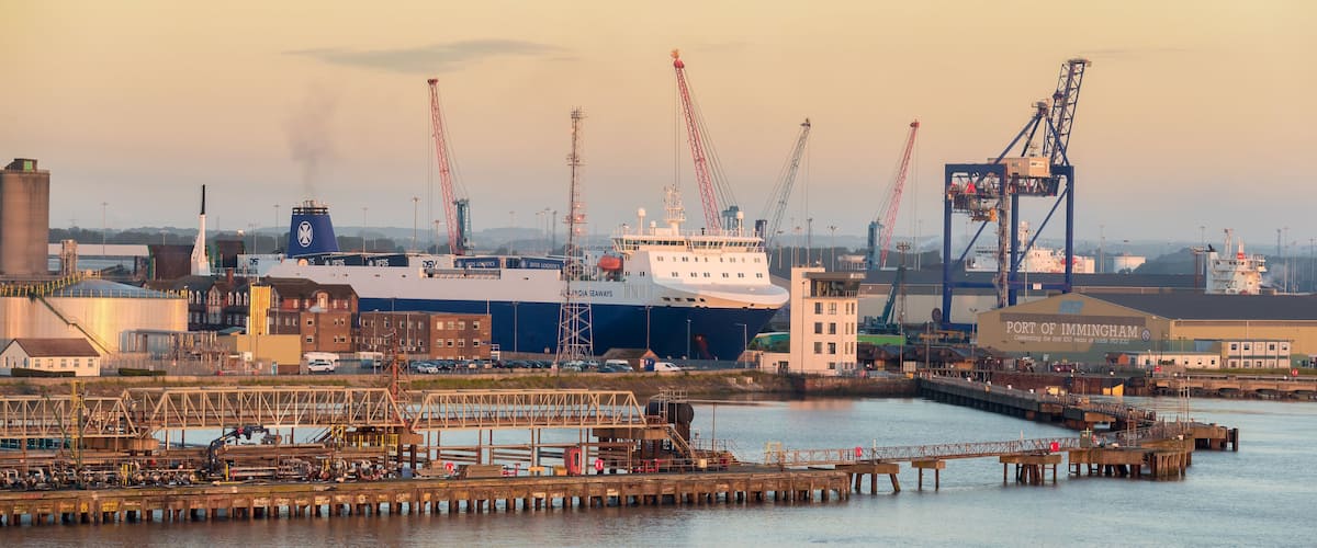 Un port où l’on peut voir un grand navire, des grues et des bâtiments industriels.