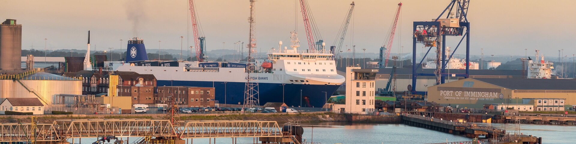 Un puerto con un gran barco, grúas y edificios industriales.