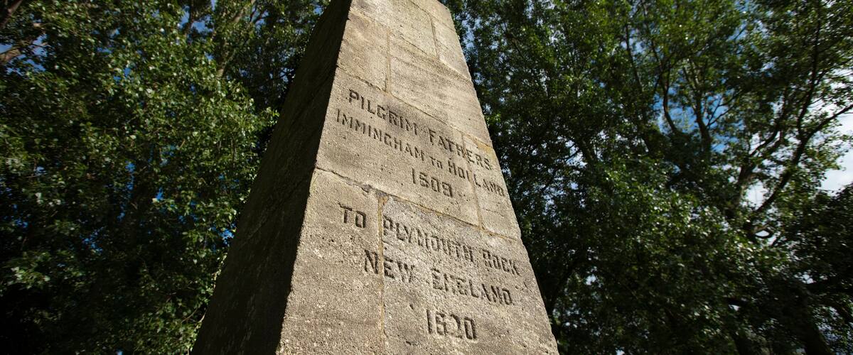 A stone monument with inscriptions, surrounded by trees.