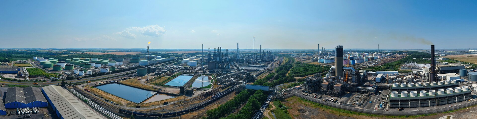 Un complejo industrial con múltiples tanques de almacenamiento, grandes edificios y un sistema ferroviario.