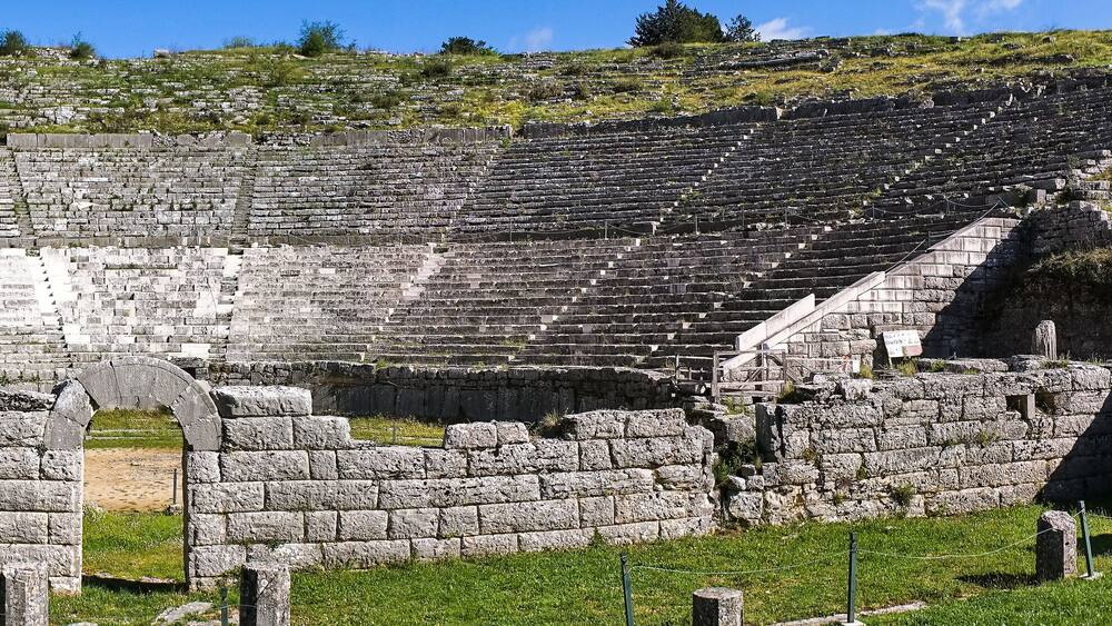 An ancient stone amphitheater with tiered seating and a central stage.