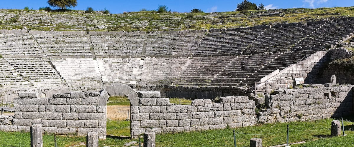 An ancient stone amphitheater with tiered seating and a central stage.