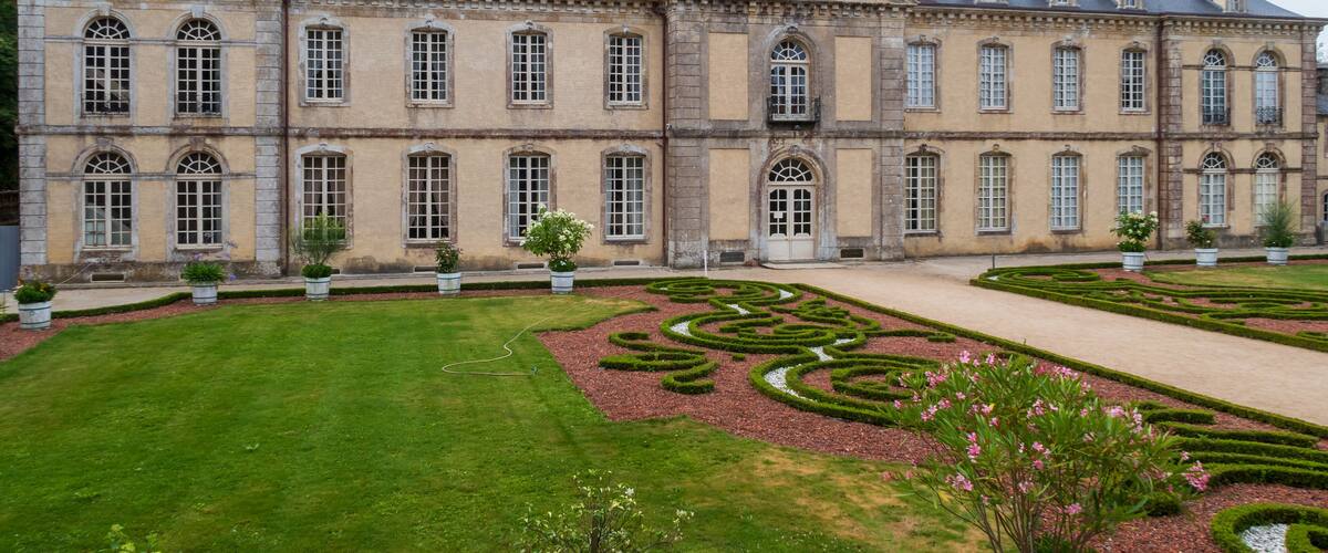 A large historic building with symmetrical gardens and a central fountain.