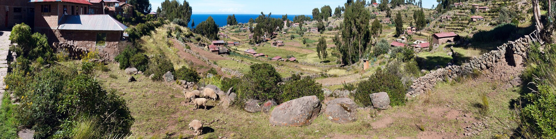 Un paisaje rural con campos en terrazas, muros de piedra y casas dispersas.