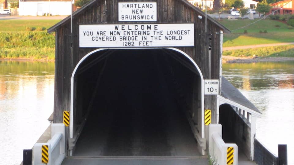 A covered bridge in Hartland, New Brunswick, with a sign stating it is the longest covered bridge in the world at 1282 feet.