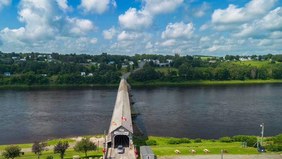 A bridge over a river with houses in the background.